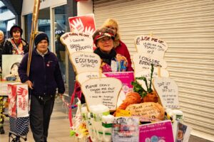 Activists in pedestrianised street, with decorated trolley. Placards read "Make Amazon pay". Trolley decorations contain advice for maximising use of a loaf of bread -- as bread puddings, eggy bread, dumplings, croutons, toast, &c