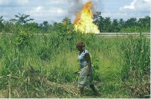 Woman walking in foreground, oil fire in background
